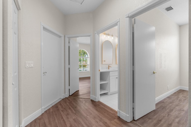 corridor with wood finished floors, visible vents, and baseboards