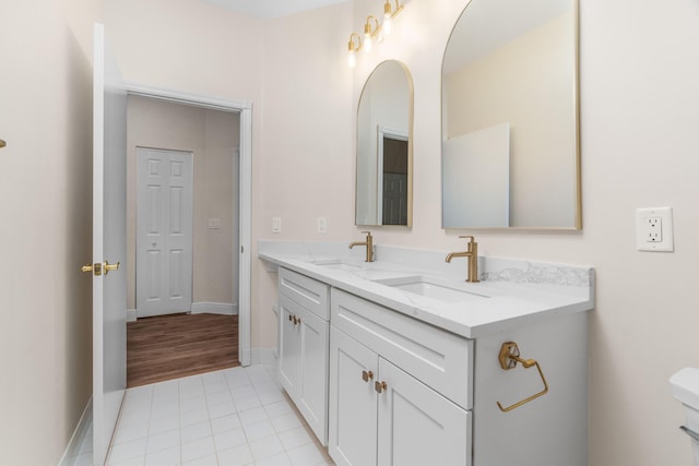 bathroom featuring tile patterned flooring, double vanity, baseboards, and a sink