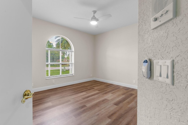 spare room featuring baseboards, wood finished floors, and ceiling fan