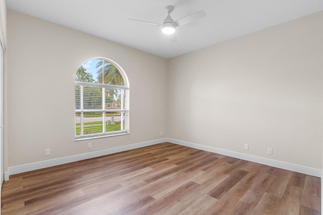 spare room featuring baseboards, light wood-type flooring, and ceiling fan