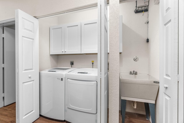 laundry room with light wood finished floors, a sink, cabinet space, and separate washer and dryer