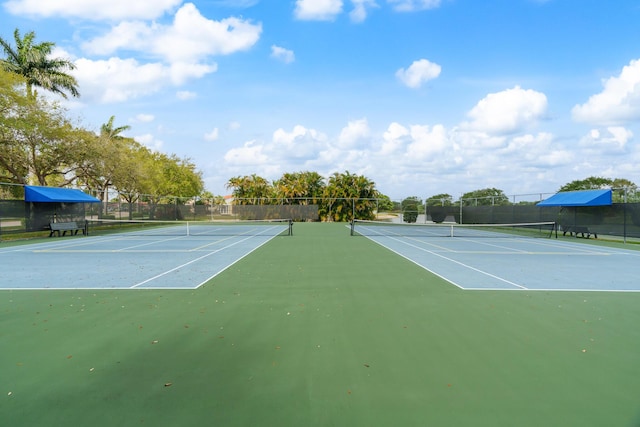 view of tennis court with community basketball court and fence