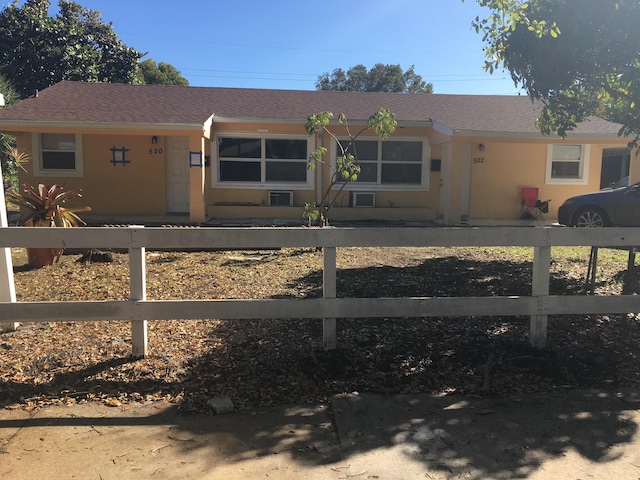 ranch-style home with a fenced front yard and stucco siding