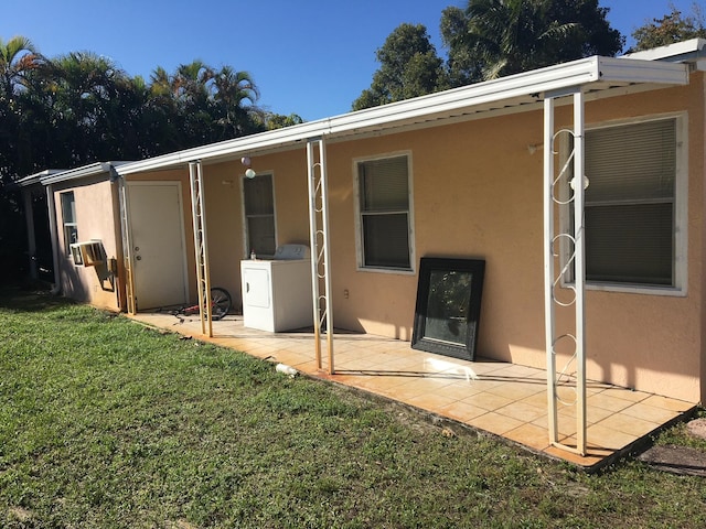 rear view of house with washer / dryer, a patio area, a lawn, and stucco siding