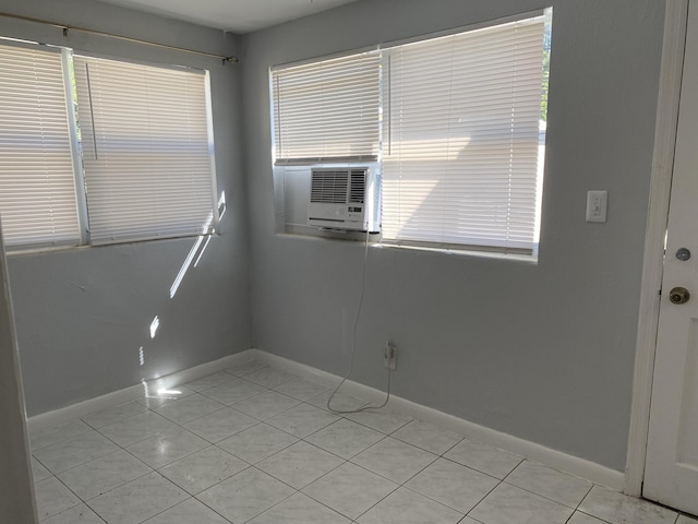 empty room featuring light tile patterned floors, cooling unit, and baseboards