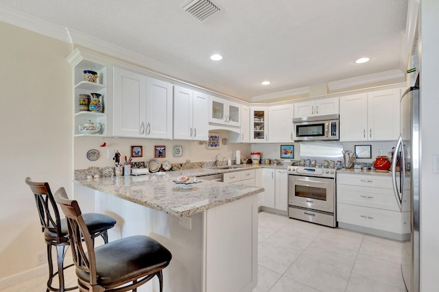 1 Church Ln Unit 111, North Palm Beach, FL 33408 - kitchen with visible vents, white cabinets, ornamental molding, appliances with stainless steel finishes, and a peninsula