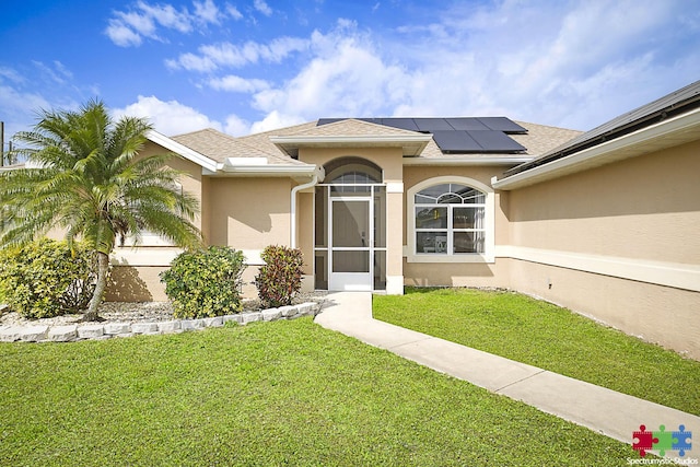 property entrance featuring stucco siding, a yard, solar panels, and roof with shingles