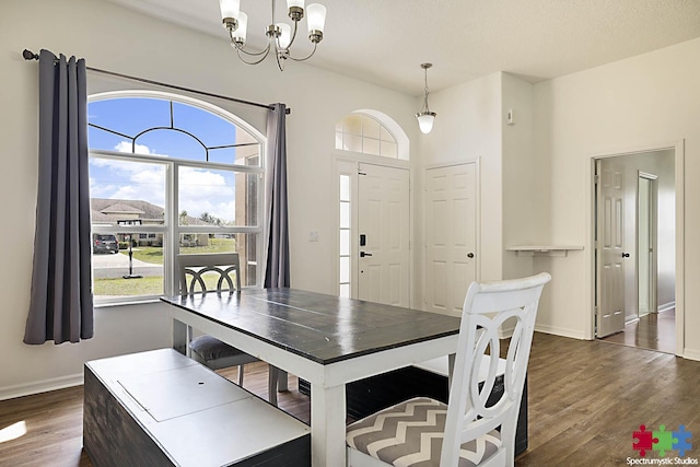 dining area featuring baseboards, a notable chandelier, and dark wood-style flooring