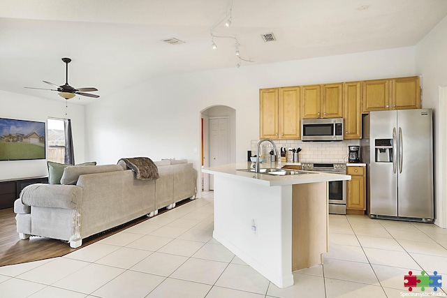 kitchen with light tile patterned floors, visible vents, arched walkways, stainless steel appliances, and decorative backsplash