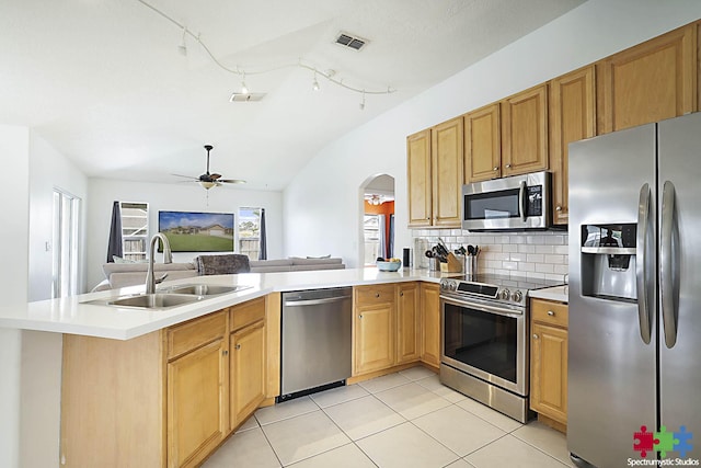 kitchen featuring backsplash, open floor plan, light countertops, appliances with stainless steel finishes, and a sink