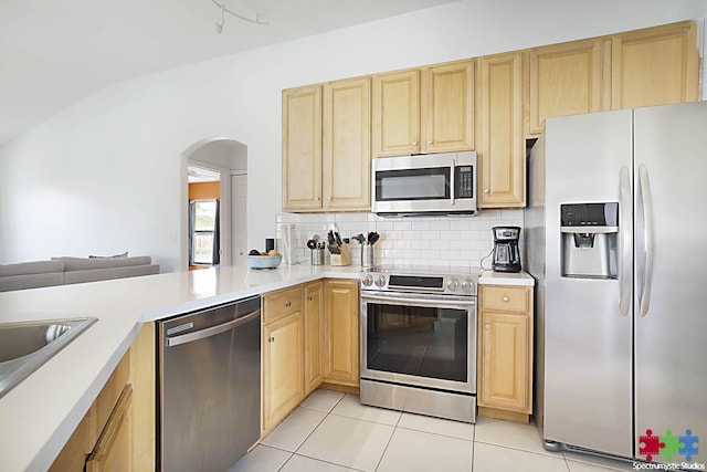 kitchen featuring light brown cabinetry, stainless steel appliances, light countertops, and tasteful backsplash