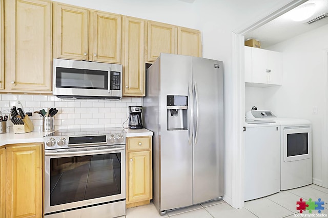 kitchen featuring stainless steel appliances, washing machine and dryer, and light brown cabinets