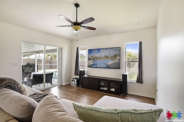 living room featuring a textured ceiling, baseboards, ceiling fan, and wood finished floors