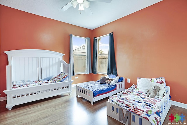 bedroom with a ceiling fan, baseboards, and wood finished floors