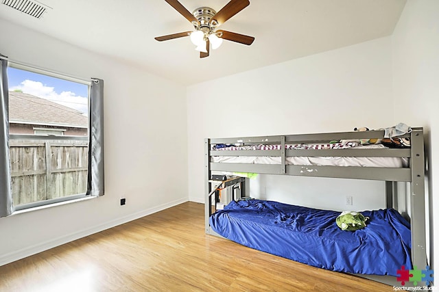 bedroom featuring a ceiling fan, wood finished floors, visible vents, and baseboards