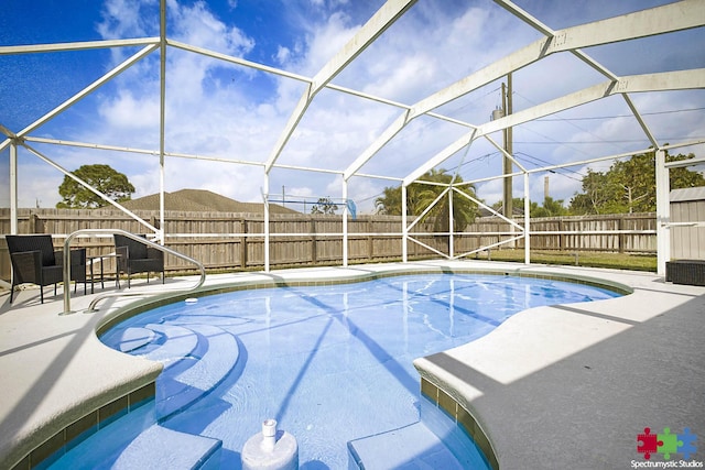 view of swimming pool featuring glass enclosure, a patio, and a fenced backyard