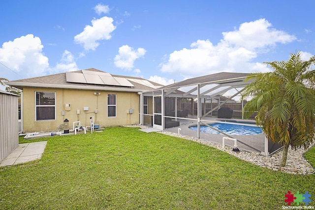 back of property featuring solar panels, stucco siding, glass enclosure, a yard, and an outdoor pool