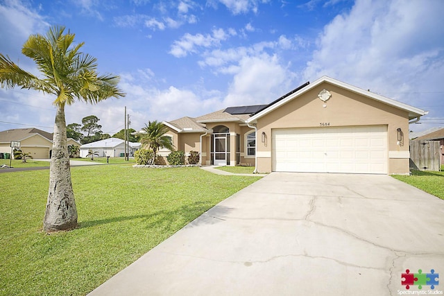 single story home with an attached garage, stucco siding, a front lawn, concrete driveway, and roof mounted solar panels