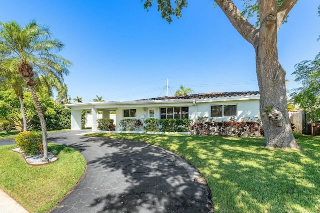 single story home featuring aphalt driveway, a front yard, and stucco siding