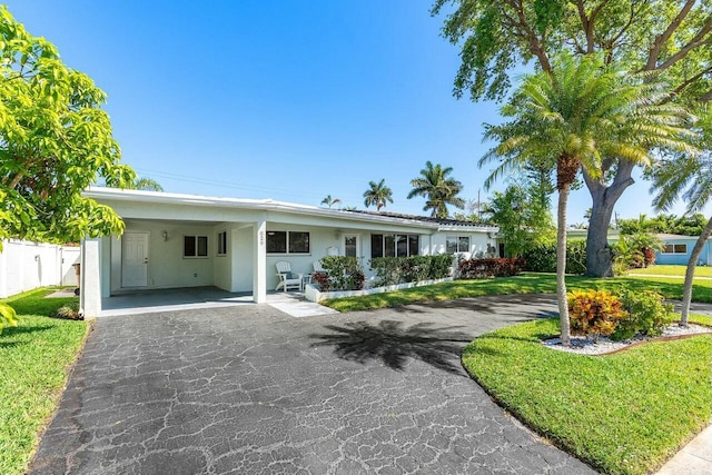 single story home featuring stucco siding, driveway, a front yard, and fence