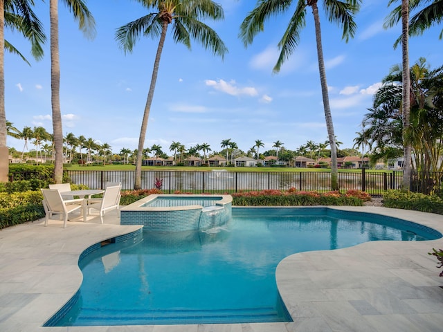 view of swimming pool with a pool with connected hot tub, a water view, a patio, and fence