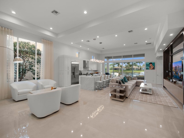 living room featuring a raised ceiling, recessed lighting, visible vents, and a towering ceiling