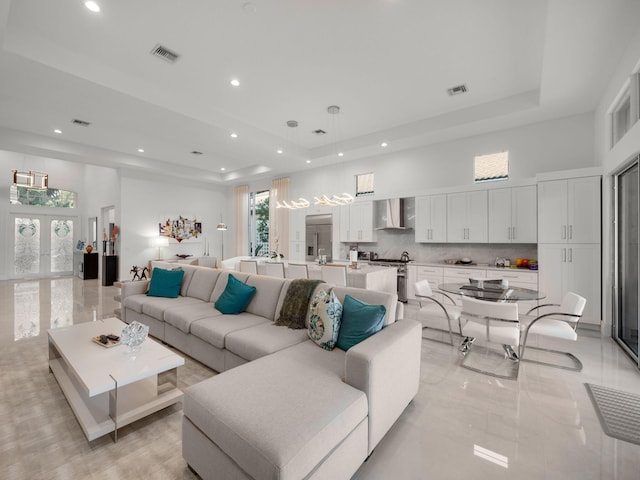 living room with a tray ceiling, visible vents, and a towering ceiling