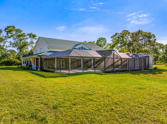 rear view of house with glass enclosure, a swimming pool, a yard, and metal roof