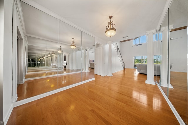 interior space featuring ornamental molding, wood finished floors, arched walkways, decorative columns, and ceiling fan