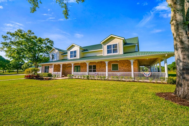 farmhouse with a front lawn, covered porch, brick siding, and metal roof