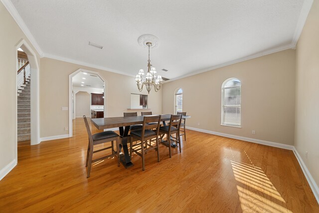 dining area with baseboards, arched walkways, light wood-style flooring, and stairs