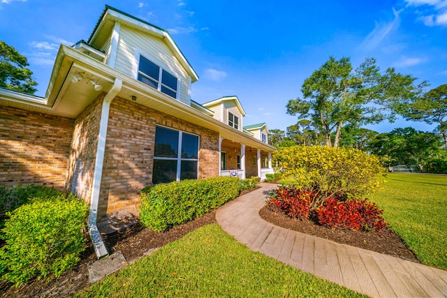 view of side of home with brick siding and a lawn