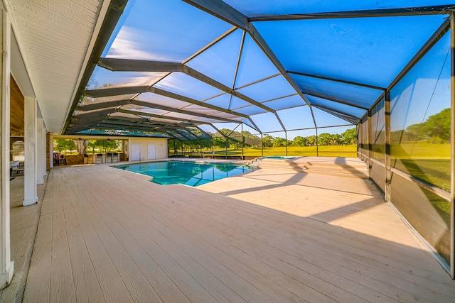 pool with a lanai, a patio, a wooden deck, and an outdoor structure