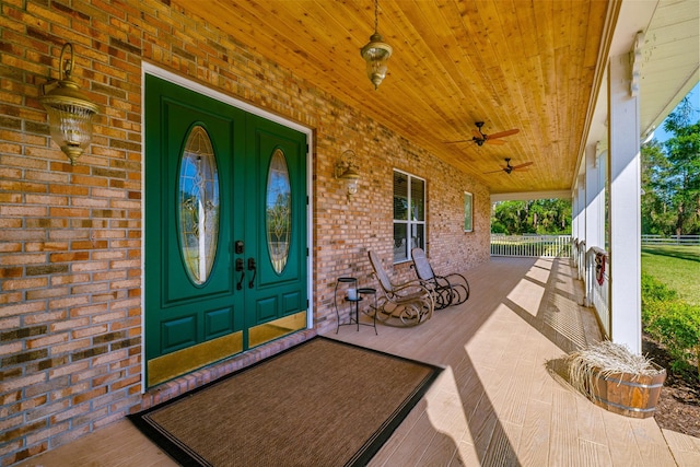 property entrance featuring covered porch, brick siding, and ceiling fan