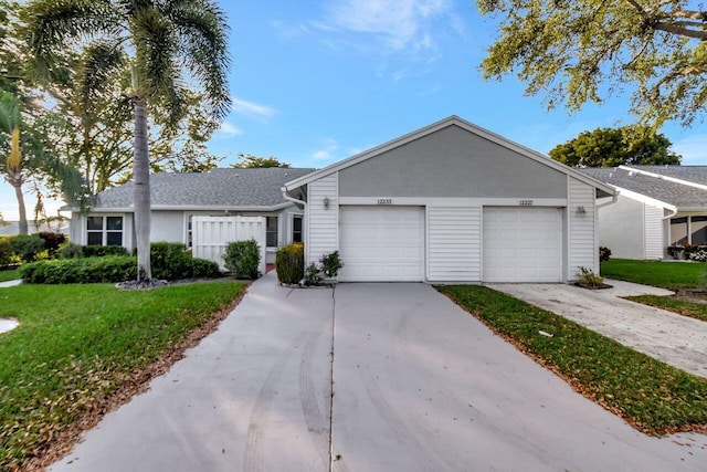 ranch-style home featuring a front yard, a garage, driveway, and stucco siding