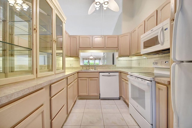 kitchen featuring light brown cabinetry, light countertops, light tile patterned floors, white appliances, and a sink