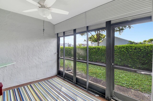 unfurnished sunroom with ceiling fan