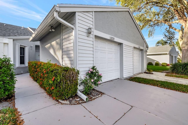 view of property exterior featuring an attached garage and concrete driveway