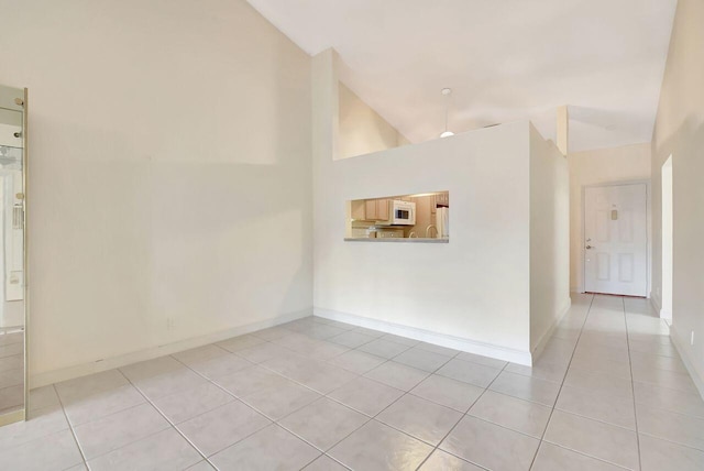 unfurnished room featuring baseboards, high vaulted ceiling, and light tile patterned flooring