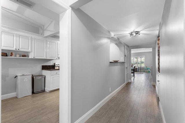 corridor with visible vents, baseboards, and light wood finished floors