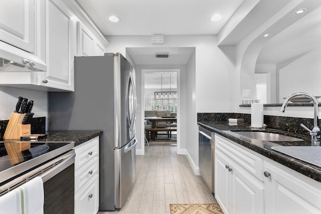 kitchen featuring under cabinet range hood, light wood-style flooring, appliances with stainless steel finishes, white cabinetry, and a sink