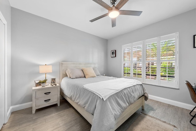 bedroom with baseboards, light wood-style floors, and a ceiling fan