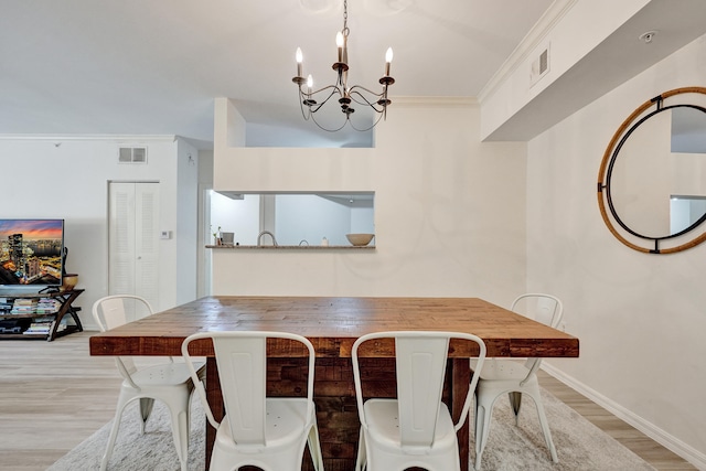 dining room featuring visible vents, crown molding, baseboards, light wood-style flooring, and a notable chandelier