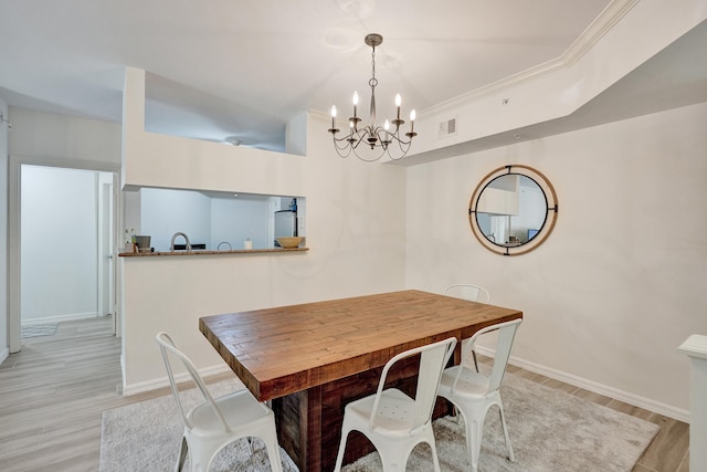 dining area featuring visible vents, light wood-style floors, crown molding, baseboards, and a chandelier