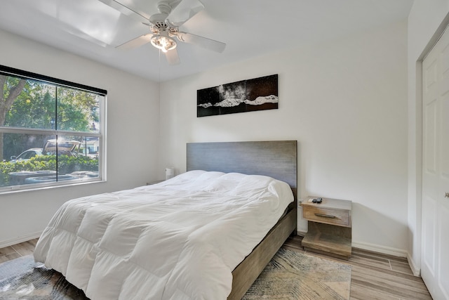 bedroom featuring baseboards, wood finished floors, and a ceiling fan