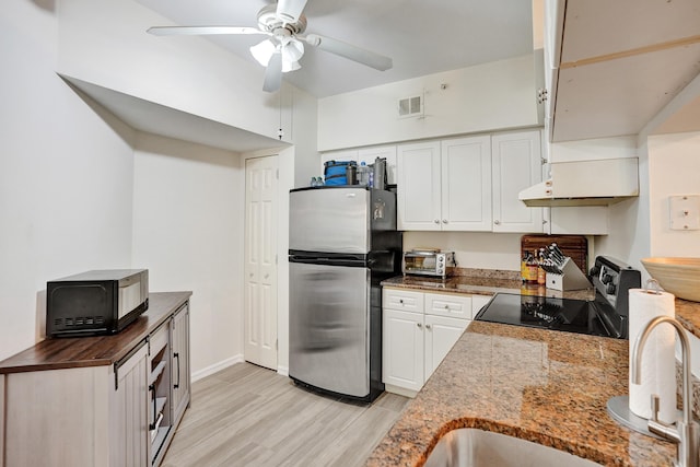 kitchen with visible vents, freestanding refrigerator, electric range oven, under cabinet range hood, and white cabinetry