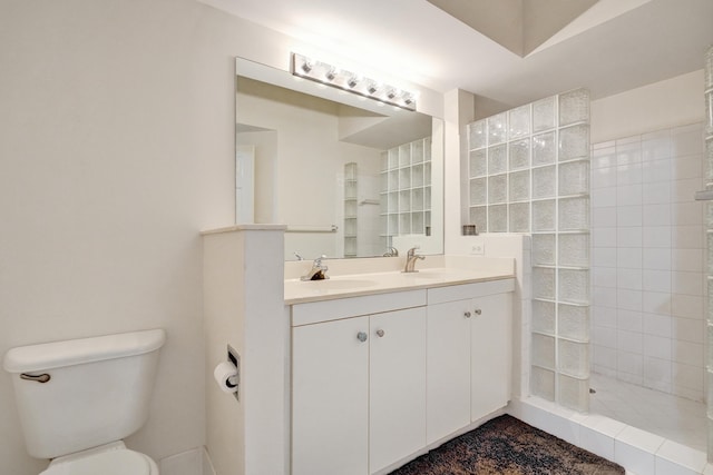 bathroom featuring double vanity, toilet, walk in shower, and a sink