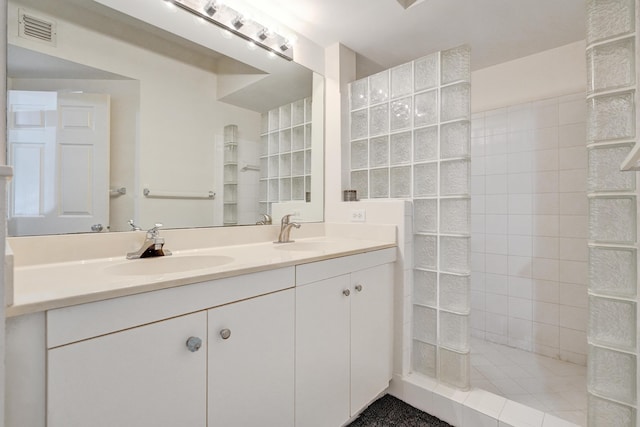 full bathroom featuring a sink, visible vents, double vanity, and a walk in shower