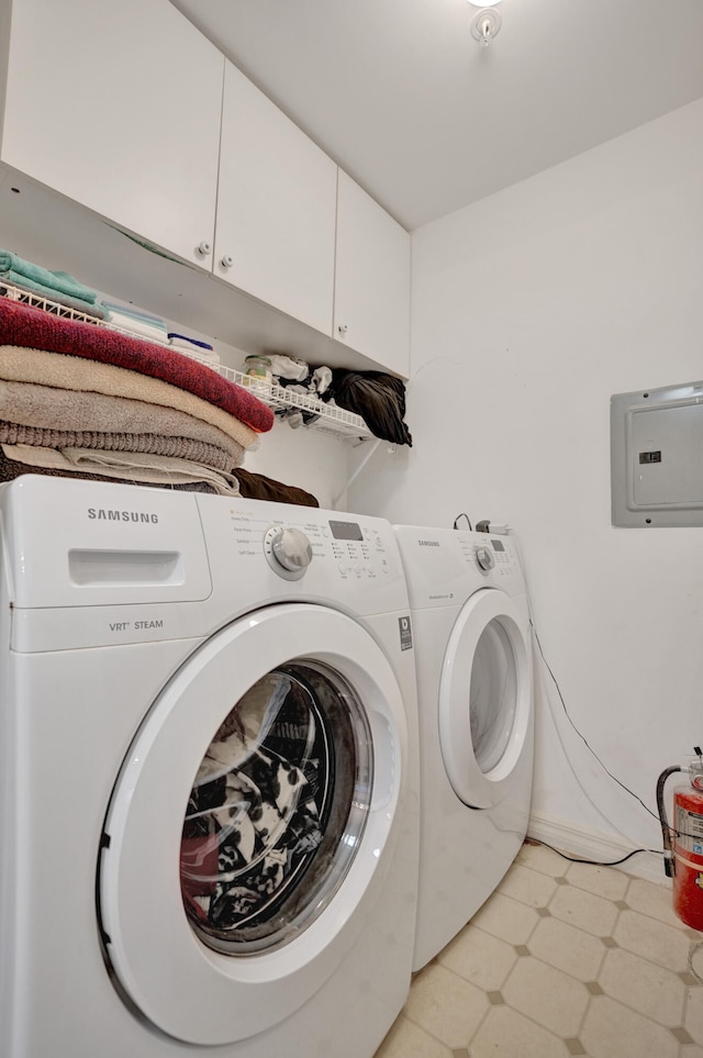 laundry area featuring washing machine and clothes dryer, cabinet space, electric panel, and light floors