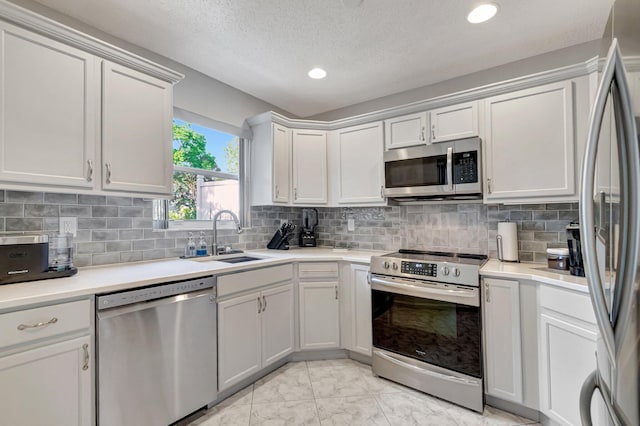 kitchen with tasteful backsplash, appliances with stainless steel finishes, light countertops, and a sink